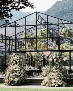 an outdoor dining area with flowers and greenery on the tables in front of it