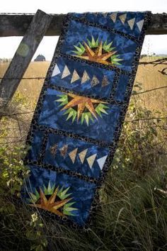 a quilt hanging on a fence in the grass