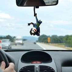 a person hanging upside down in the air from a car dash board on a highway