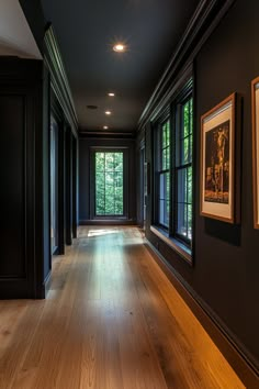 an empty room with wood floors and black walls, framed pictures on either side of the wall