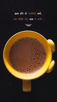 a yellow cup with liquid in it on a black table next to a quote about coffee