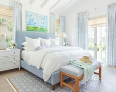 a bedroom with white bedding and blue curtains