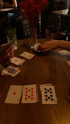 people playing cards at a table with wine glasses