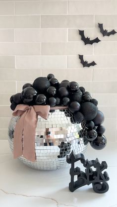 a mirror ball and some black balloons in front of a white wall with bats on it