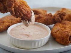 fried chicken sticks being dipped with dipping sauce