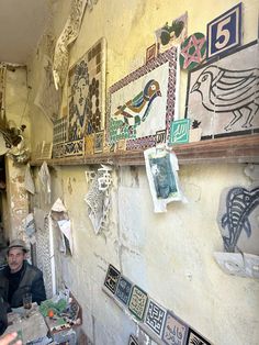 two men are sitting at a table in front of some art work on the wall