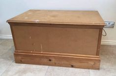 a wooden box sitting on top of a tile floor next to a wall and door