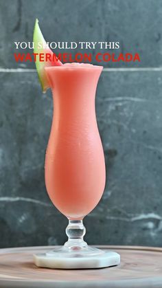 a pink drink sitting on top of a wooden table next to a gray wall with the words you should try this watermelon cola