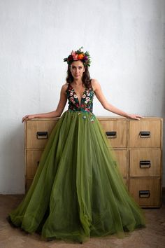 a woman wearing a green dress standing in front of a dresser