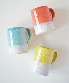 three different colored coffee mugs sitting next to each other