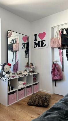 a bedroom with two mirrors and pink bags on the shelf next to eachother