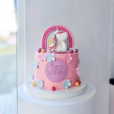 there is a pink cake with a unicorn on it