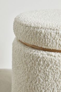 a white ottoman with a wooden lid on the top and bottom, covered in sheep fur