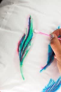 someone is painting some feathers on a white sheet with blue, green and pink colors