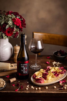 a bottle of wine sitting next to a plate of food and a vase with flowers