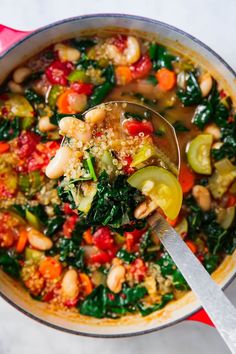 a spoon full of soup with vegetables and grains