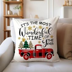 a red truck with christmas trees on the back is sitting on a white couch in front of a bookcase