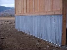 the side of a building that is made out of wood and metal sidings, with mountains in the background