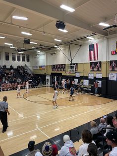 a group of people playing basketball on a court with an audience in the bleachers