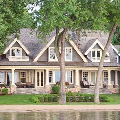 a large house sitting on top of a lush green field next to a lake in front of a forest