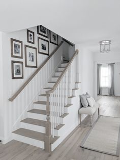 a living room with stairs and pictures on the wall