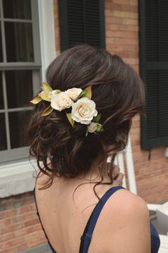 a woman with flowers in her hair wearing a blue dress and looking out the window