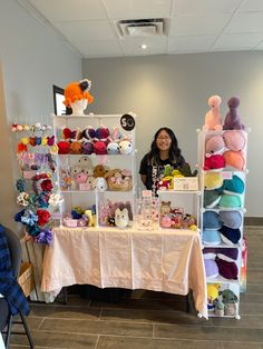 a woman standing behind a table with stuffed animals on it