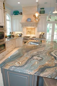 a large kitchen with marble counter tops and white cabinetry, along with stainless steel appliances