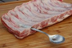 a piece of raw meat on a cutting board with a spoon