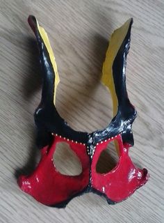 a red and black mask sitting on top of a wooden table