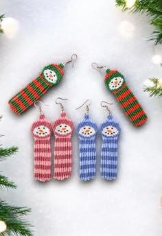 three knitted snowmen are hanging from the christmas tree, and one is wearing mittens