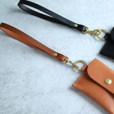 two different types of leather purses on a white surface with one black and one brown