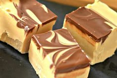 four pieces of chocolate covered dessert sitting on top of a black plate next to each other