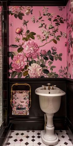 a bathroom with pink flowers on the wall and white pedestal sink in front of it