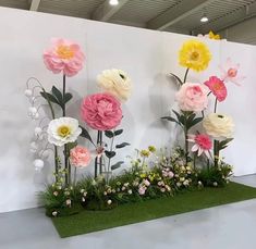 flowers are arranged on the wall in front of artificial grass and fake flowers for display