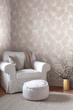 a living room with a white chair and ottoman next to a wallpapered wall