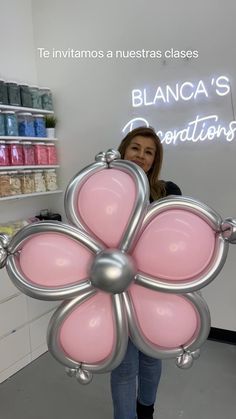 a woman holding a pink flower shaped object in front of a store display with the words blancca's creations written on it