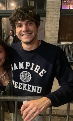 a man and woman standing next to each other in front of a gate with the words vampire weekend written on it