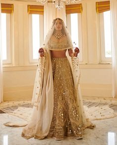 a woman in a gold and white bridal gown standing next to a chandelier