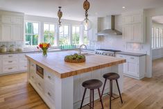 a large kitchen with white cabinets and wooden counter tops