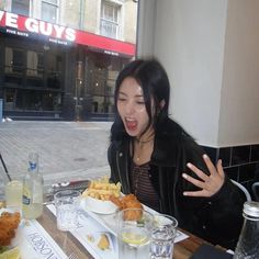 a woman sitting at a table in front of a plate of food with her mouth open