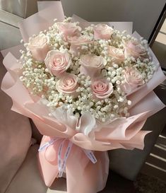 a bouquet of pink roses and baby's breath is sitting on a car seat