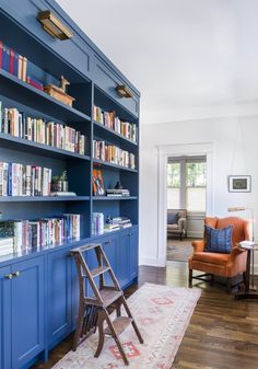 a living room with blue bookshelves and chairs