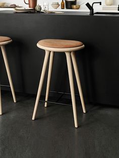 two stools in front of a counter with pots and utensils on it