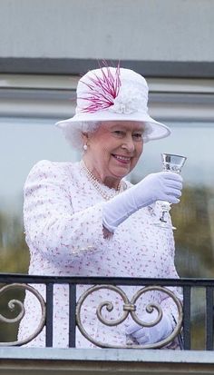 an older woman wearing a white hat and holding a wine glass in her right hand