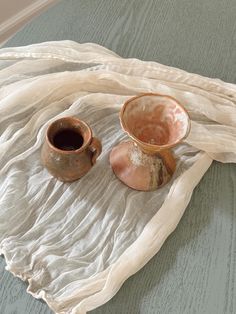 two brown cups sitting on top of a white cloth