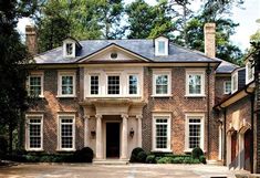 a large brick house with lots of windows on it's front door and driveway