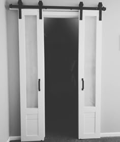 an empty room with two white doors and black hardware on the sliding glass door handles