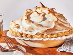 a pie sitting on top of a wooden table next to a glass filled with liquid