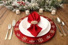 a red and white place setting on a wooden table with christmas decorations in the background